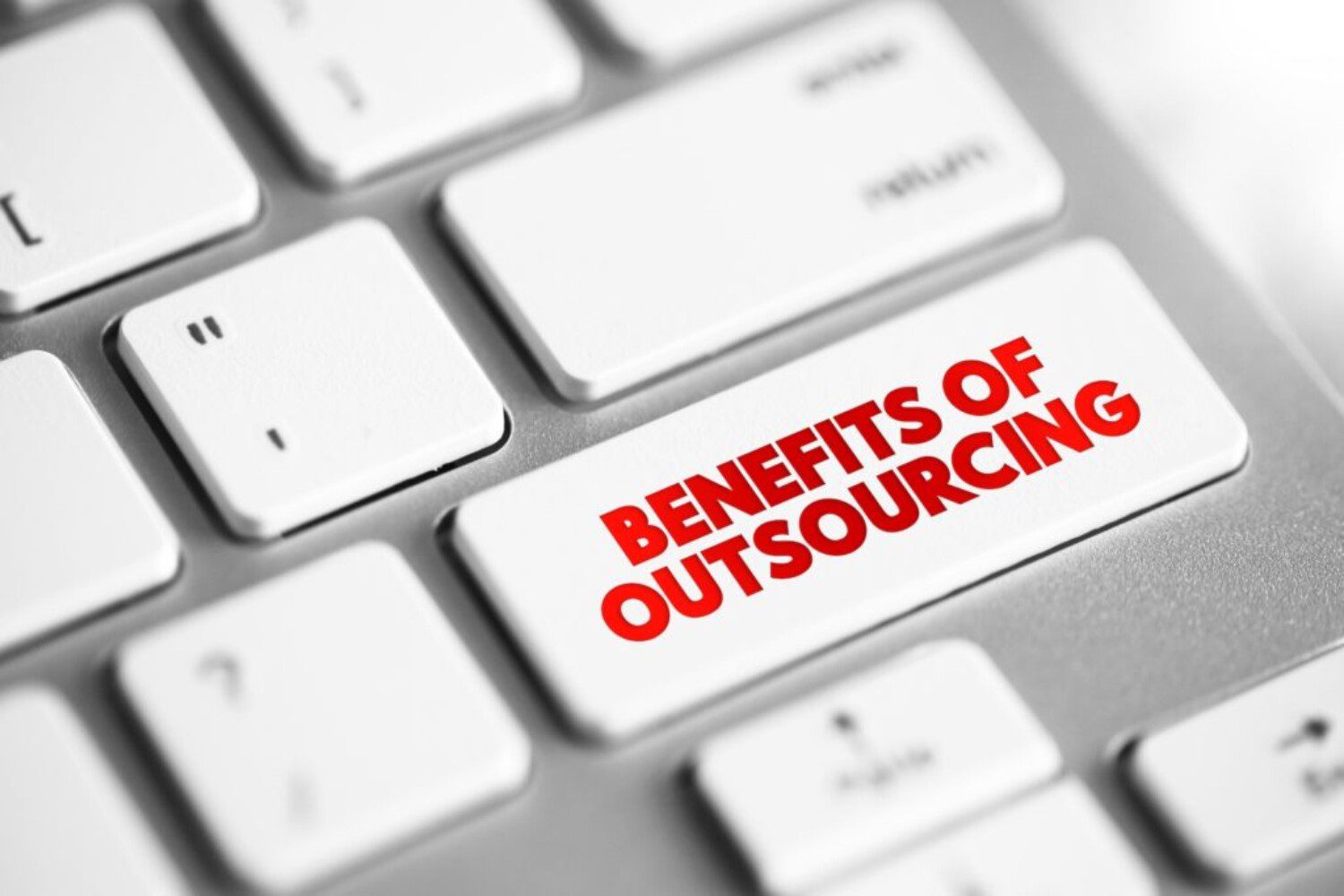 Close up a a keyboard button with "benefits of outsourcing" on it