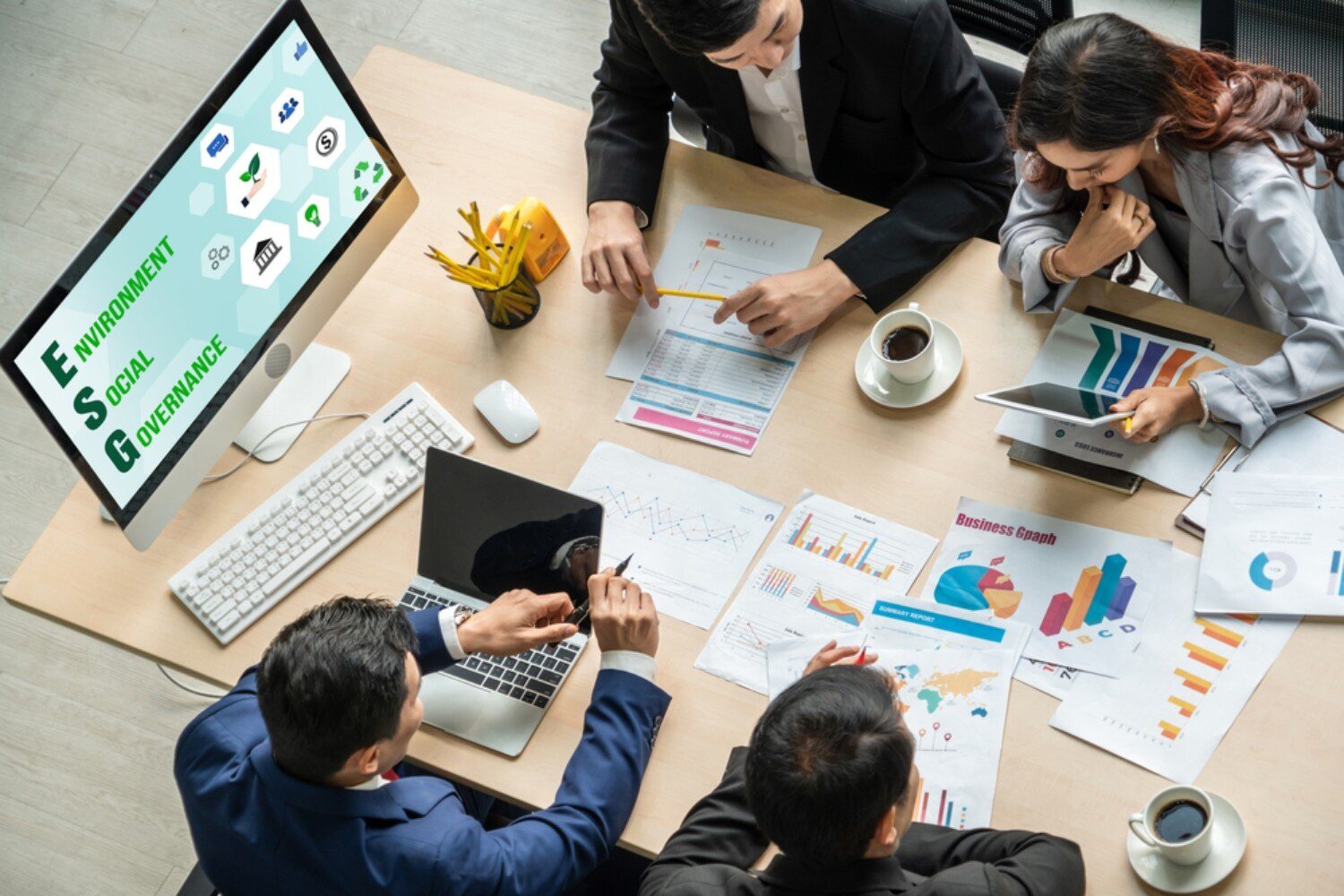 four people meeting while looking at charts, graphs, and a computer