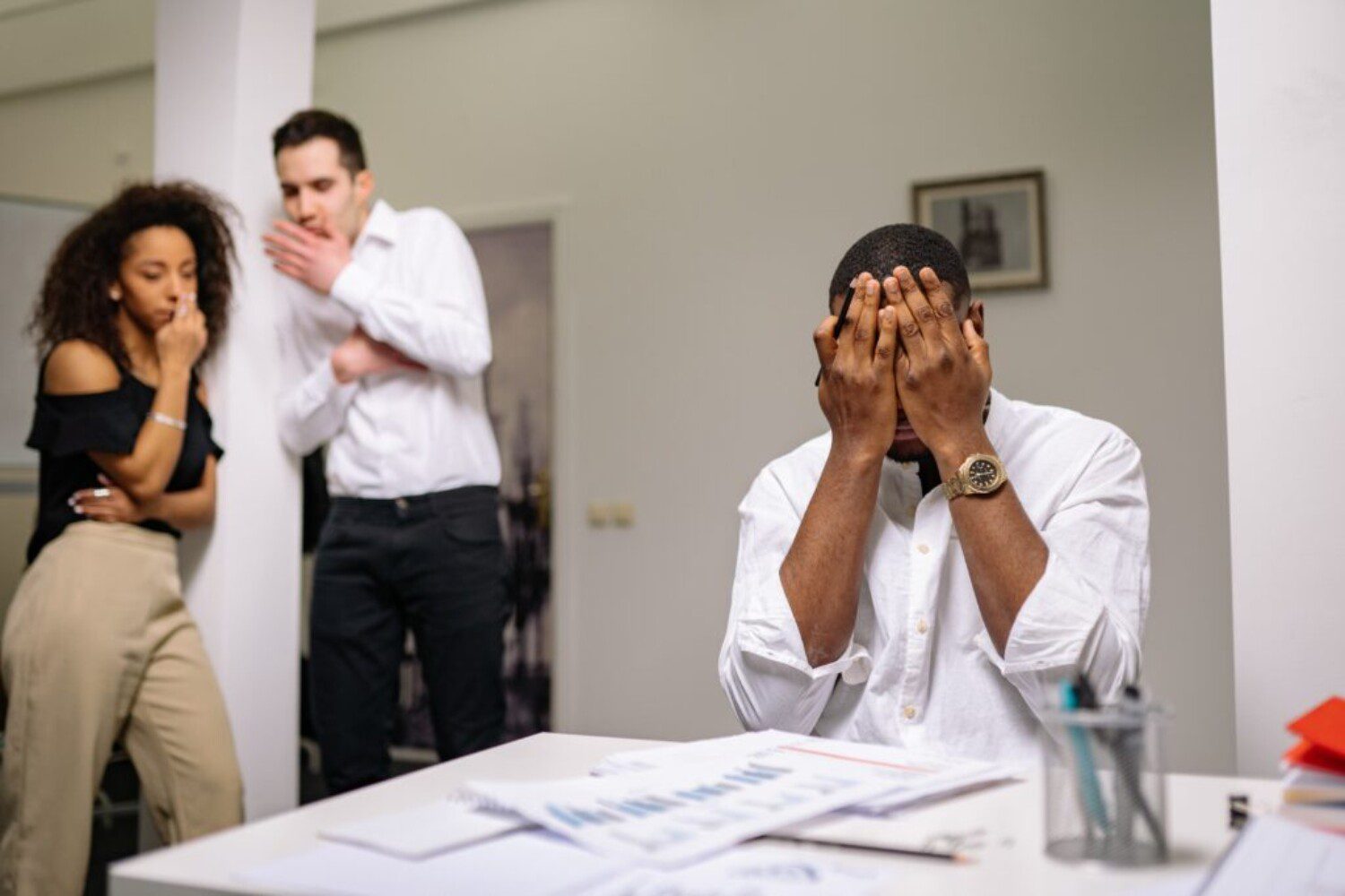 man in a white shirt covering his face