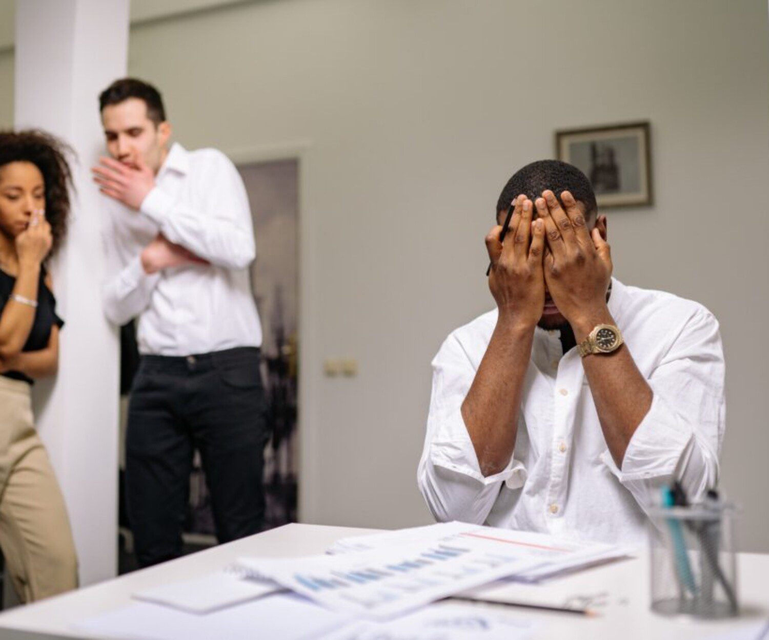 man in a white shirt covering his face