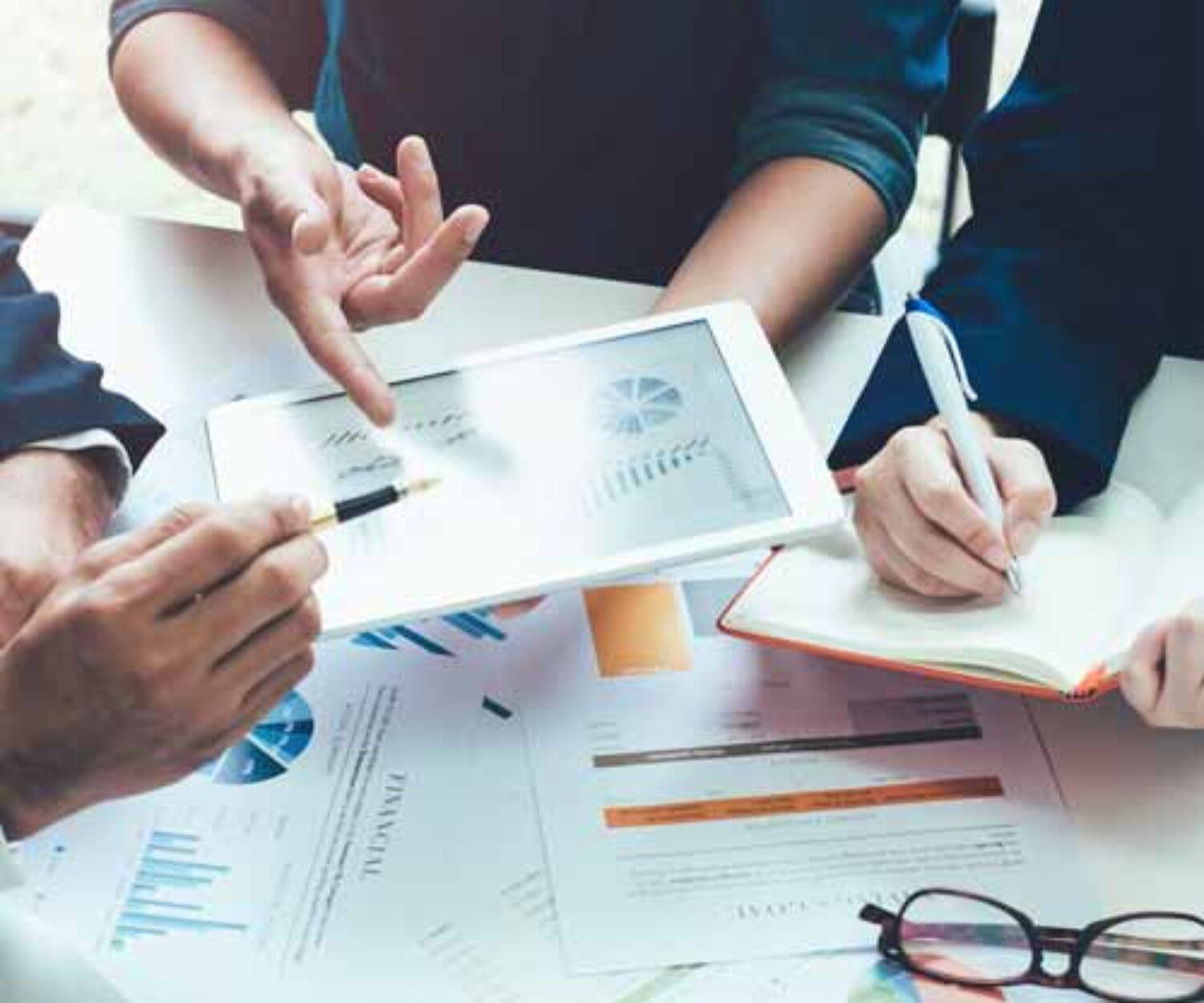 people looking at an iPad with a chart on it with someone taking notes