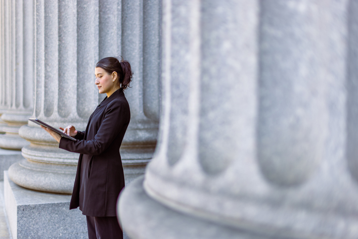 Woman standing next to white pillars on her iPad