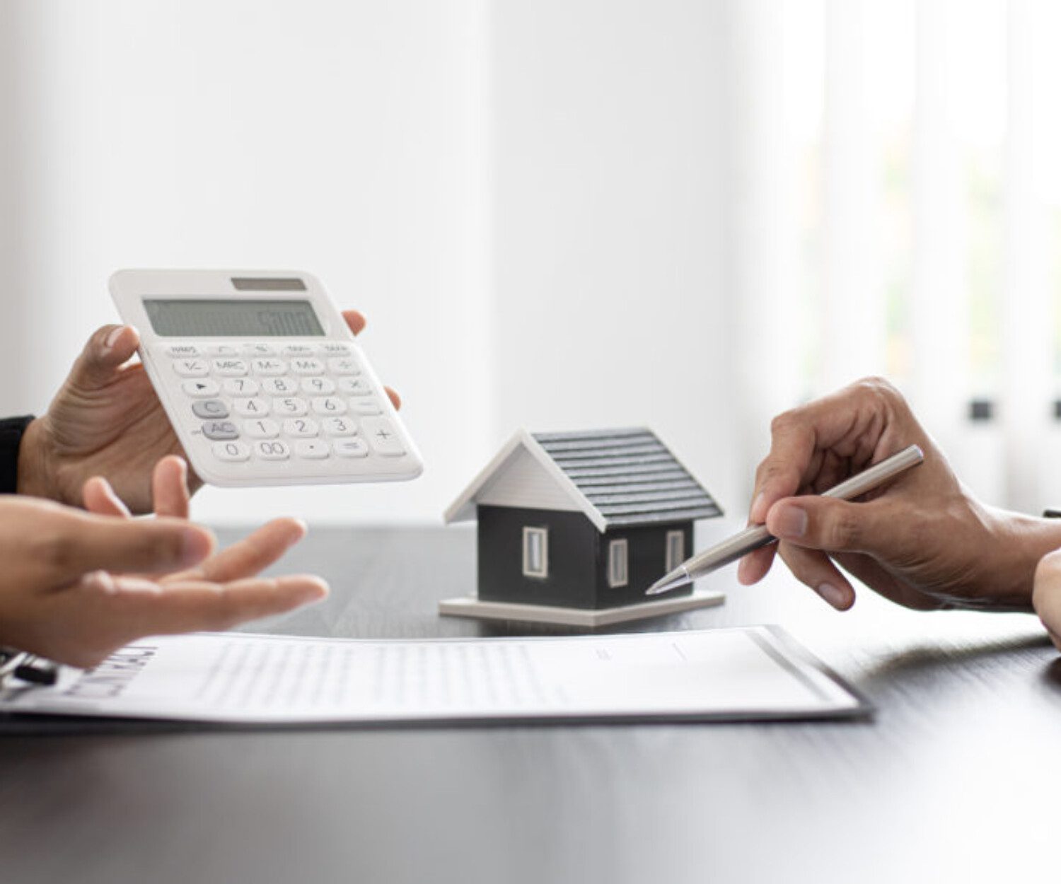 someone holding a calculator and someone holding a pen looking at a sheet of paper