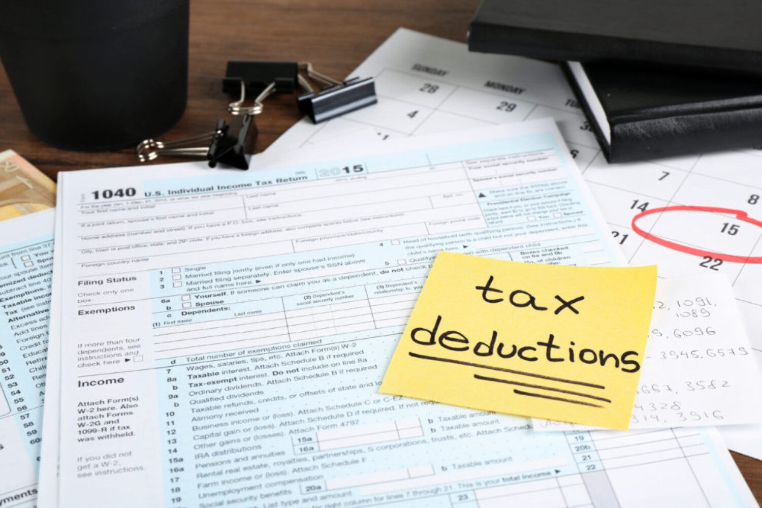 yellow sticky note that says "tax deductions" on top of documents
