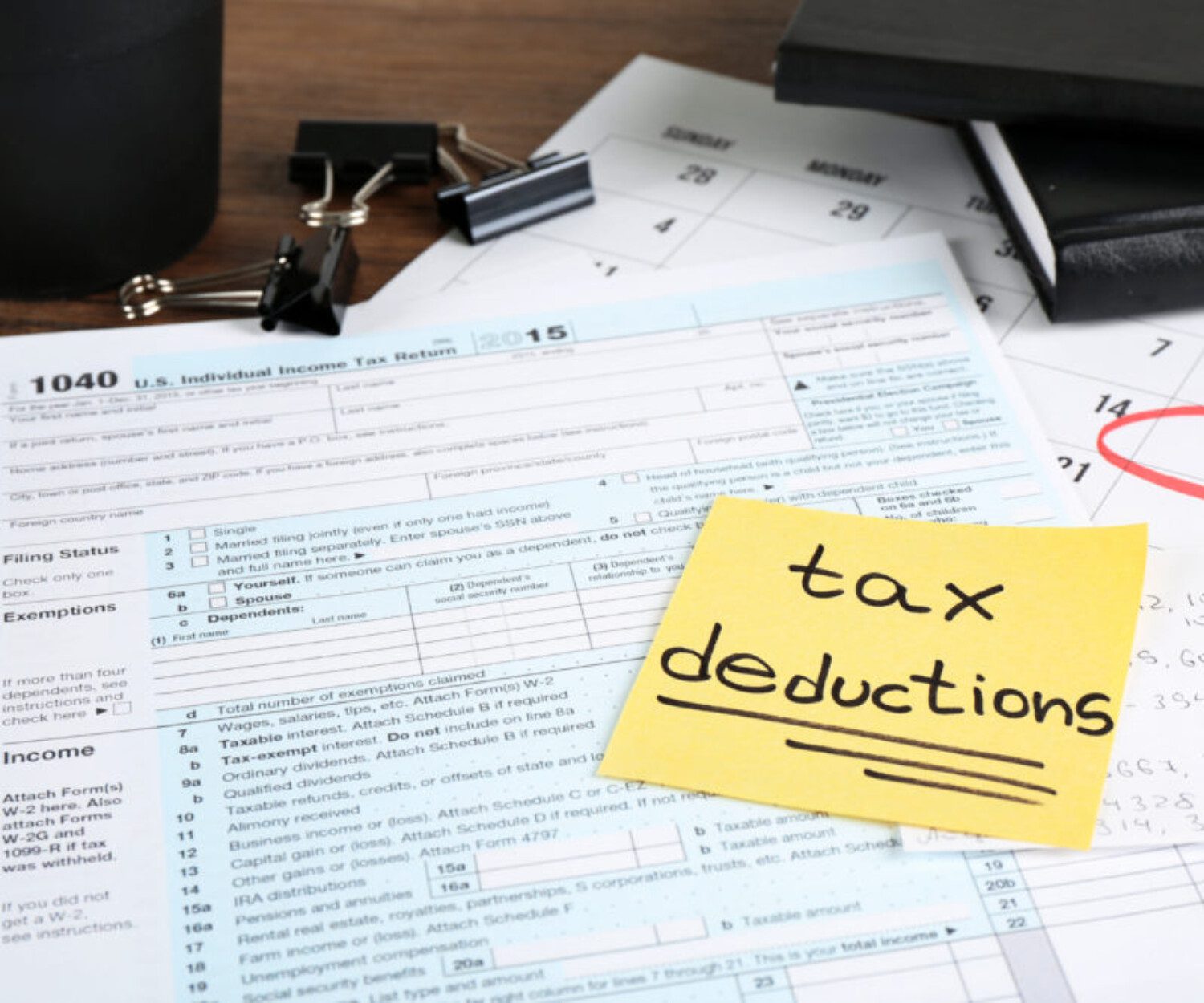 yellow sticky note that says "tax deductions" on top of documents