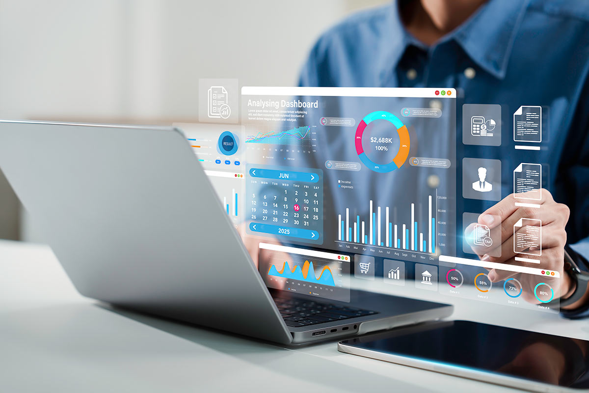 A person interacts with a futuristic dashboard displaying financial data and analytics on a laptop, with mobile device nearby.
