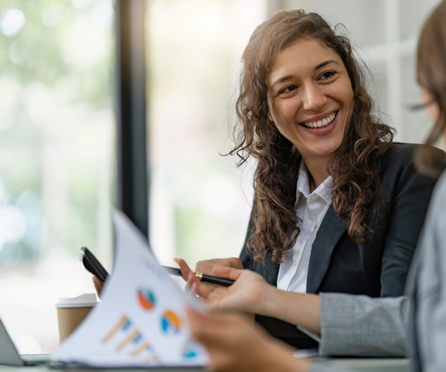 A woman with brown hair smiles at another person