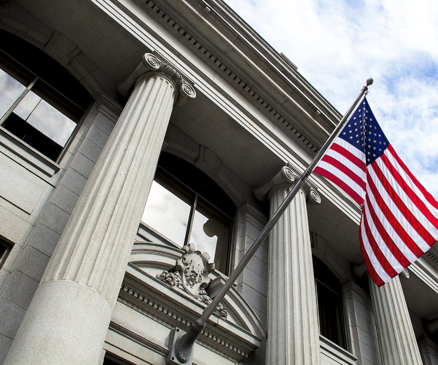 A white government building with columns and a US flag waving outsite