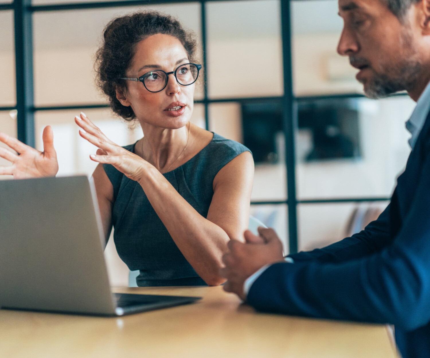 Two business people having a meeting and discussing new agreement. Working process in the office, businessman and business woman working together using laptop. Couple of business persons talking, they are engaged in a focused conversation