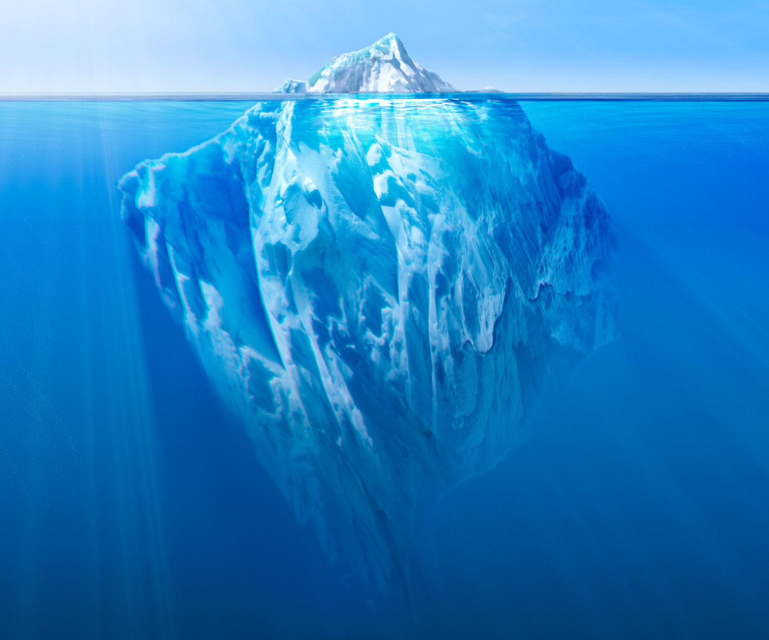 A massive iceberg floating in the water, with a small visible tip above water and a vast submerged section beneath.
